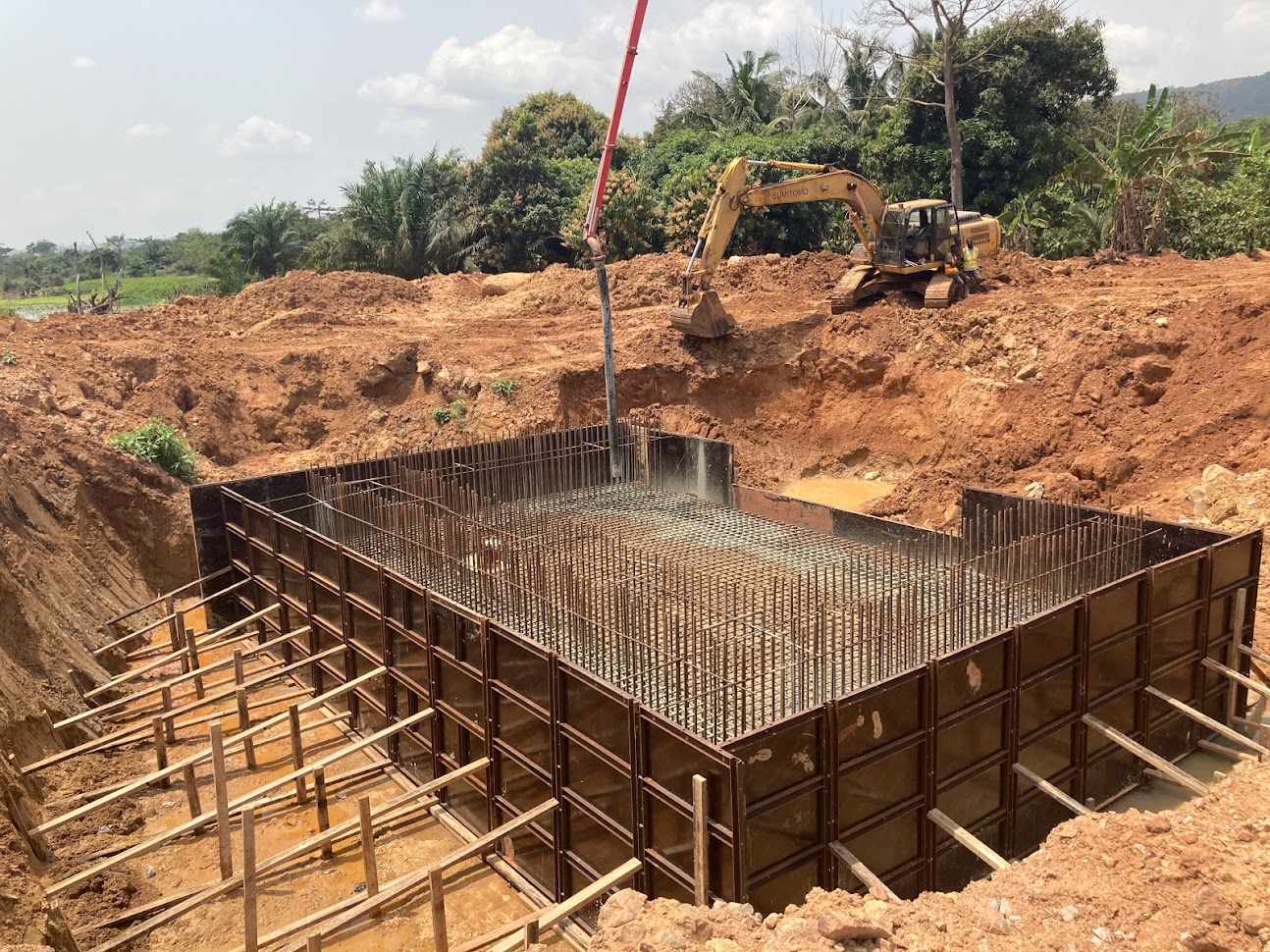 Reinforced concrete culvert and foundation construction with concrete pump and excavator on a civil engineering project in West Africa