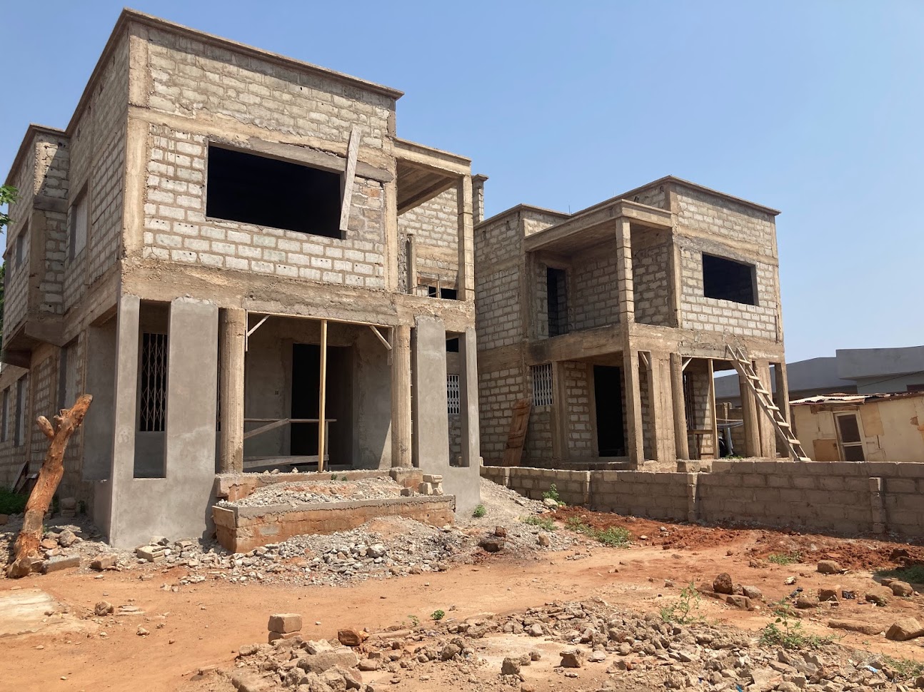 Two-storey residential building under construction with reinforced concrete frame columns and masonry block walls in Accra, Ghana
